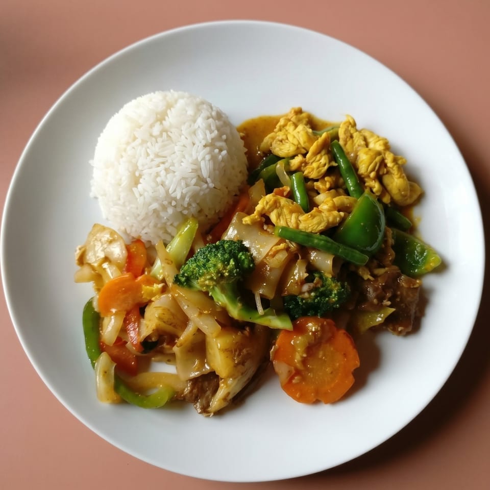A white plate with rice, yellow curry chicken, and stir-fried vegetables.