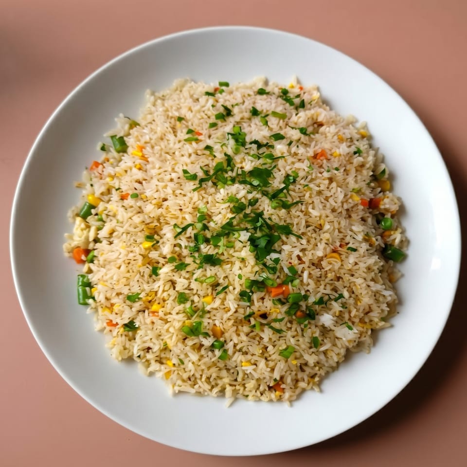 A white plate filled with fried rice, garnished with chopped green onions and parsley.